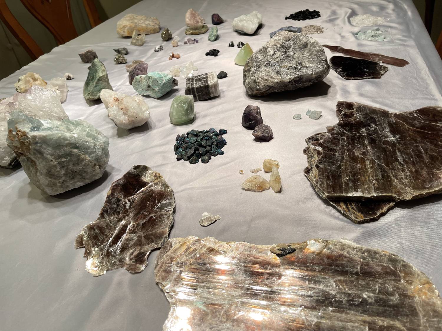 Photograph of a table with minerals and gems of varying shapes, colors, and sizes.