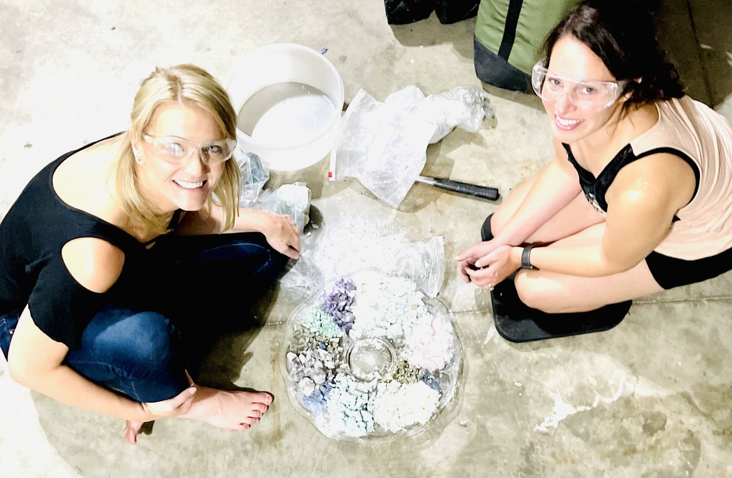 Overhead photo of Tammy Campbell smiling at the camera sitting in front of a platter of smashed gemstones with another person opposite.