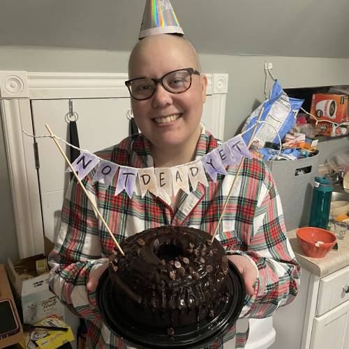 Photo of Inspiration Brenna Donegan with a birthday hat on, holding a chocolate cake